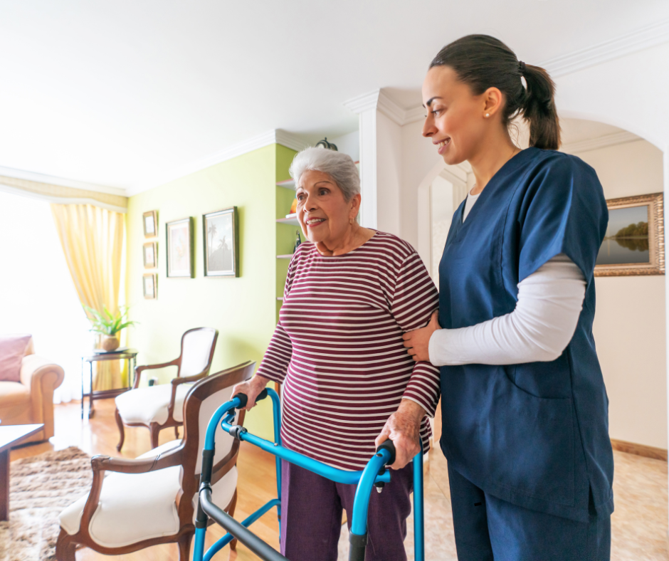A supportive caregiver in scrubs assisting an elderly woman with a walker inside a senior living community during hurricane season.